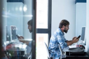 Male It Technician At Computer In Office Working On Cybersecurity Solutions For Company